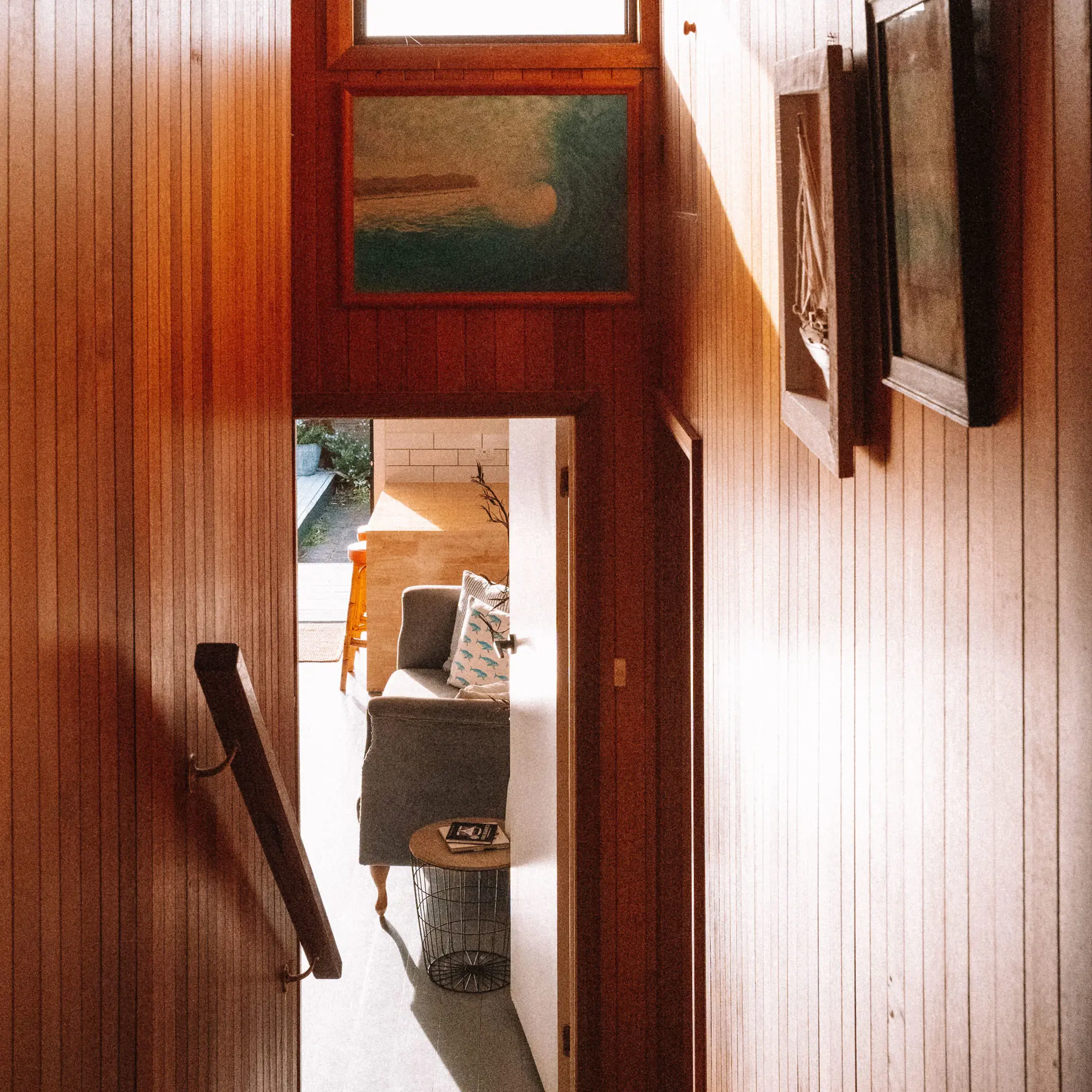 A narrow wooden interior hallway with timber walls and a small window at the far end above wooden flooring.