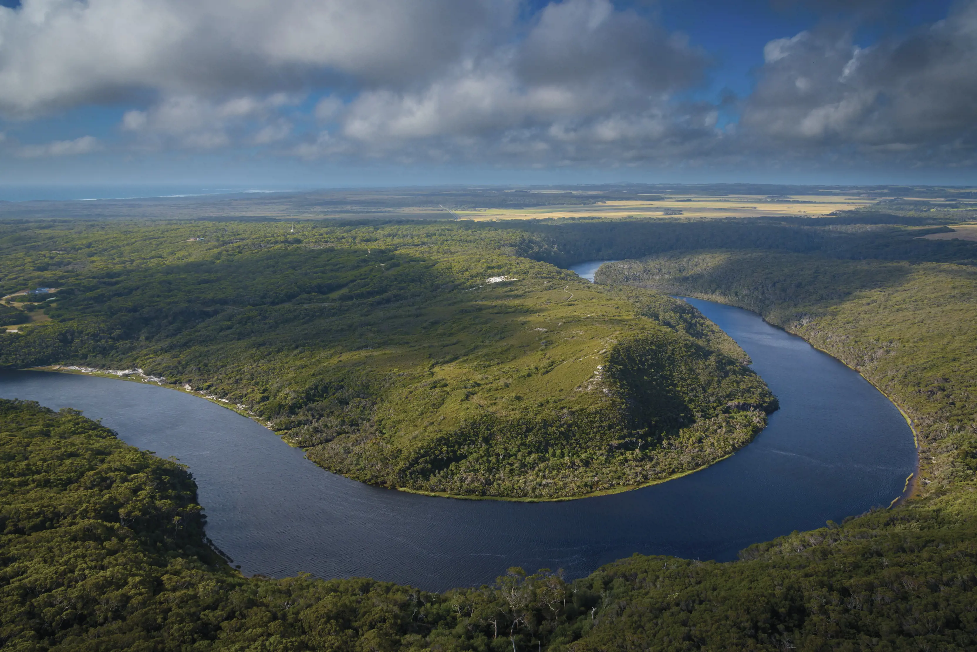Birdseye view of Arthur River and surrounding trees, partially shadowed by clouds.